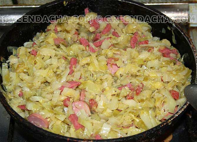 Всыпаем в капусту сосиски и колбасу.